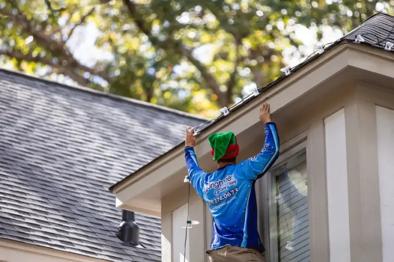 Brightview installer hanging Christmas lights along a roofline