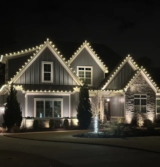 Home with warm white Christmas lights along the rooflines at night