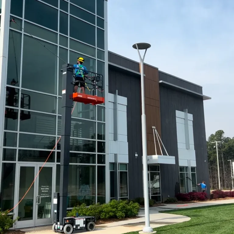 Brightview technician cleaning the glass of a modern commercial building from a lift