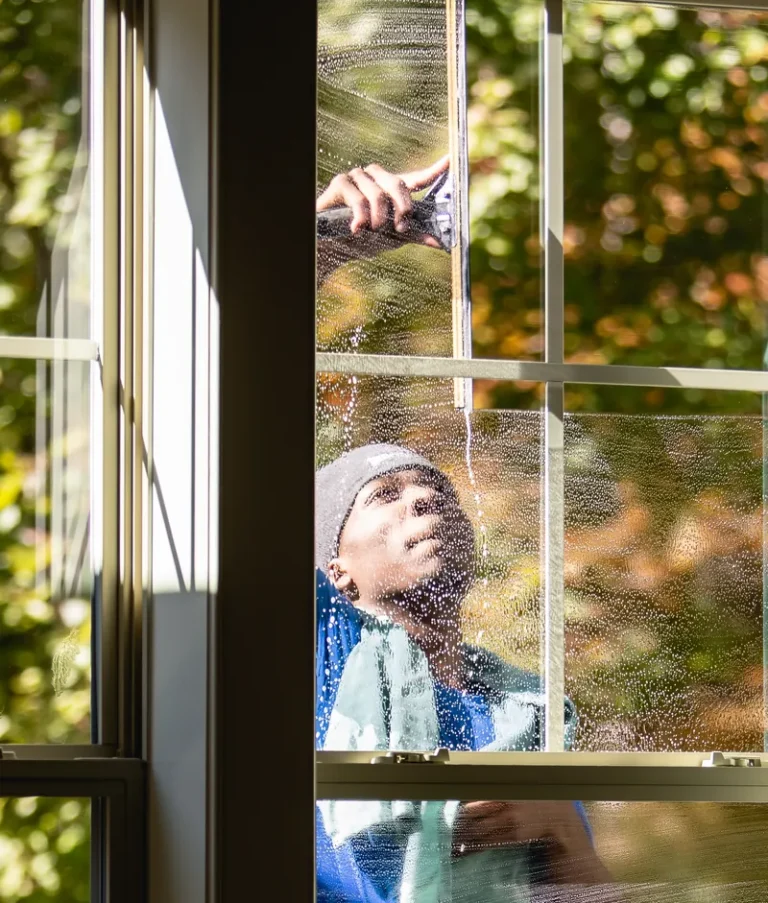 Brightview technician cleaning the outside of a window, seen from inside the home