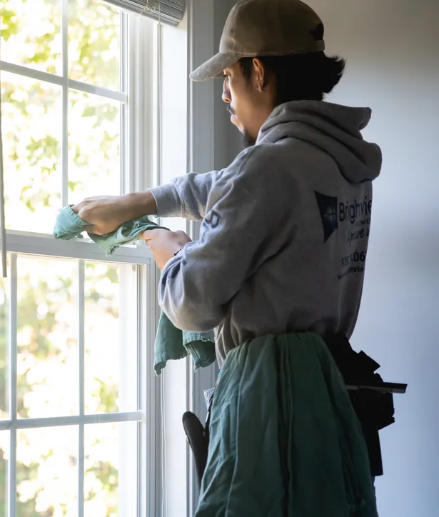 Brightview technician wiping a window from inside a bright home