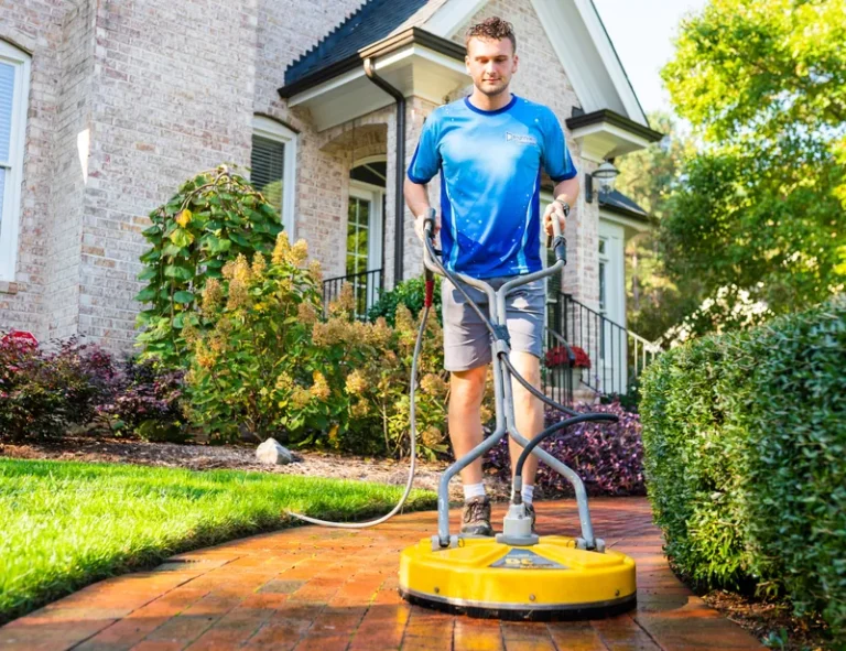 Brightview technician running a surface cleaner over a brick walkway